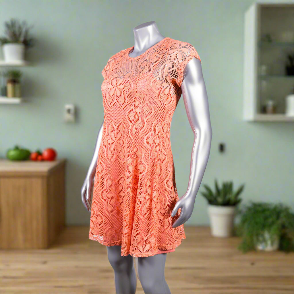 Coral lace dress on a mannequin against a white background
